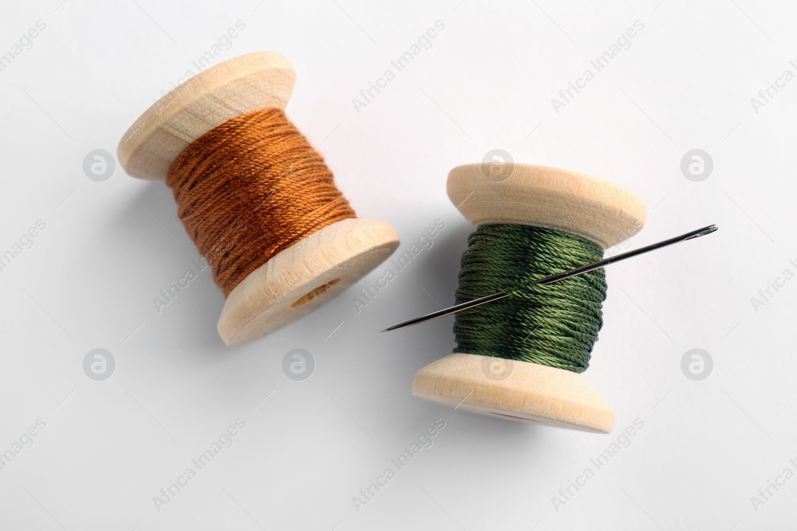 Photo of Colorful sewing threads with needle on white background, top view