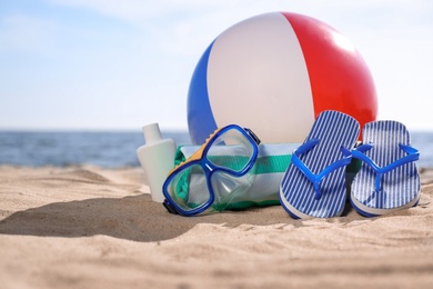 Inflatable ball and beach objects on sand near sea, space for text