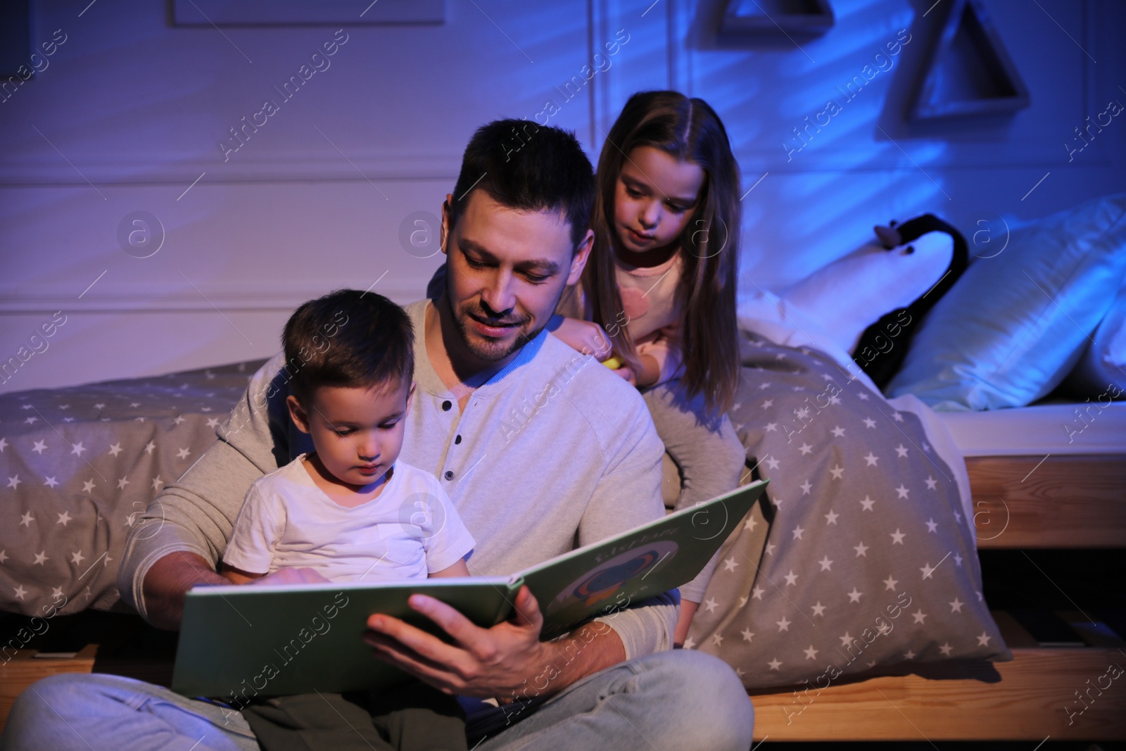 Photo of Father reading bedtime story to his children at home