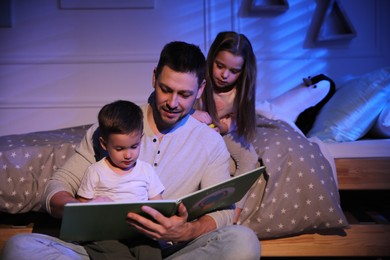 Photo of Father reading bedtime story to his children at home