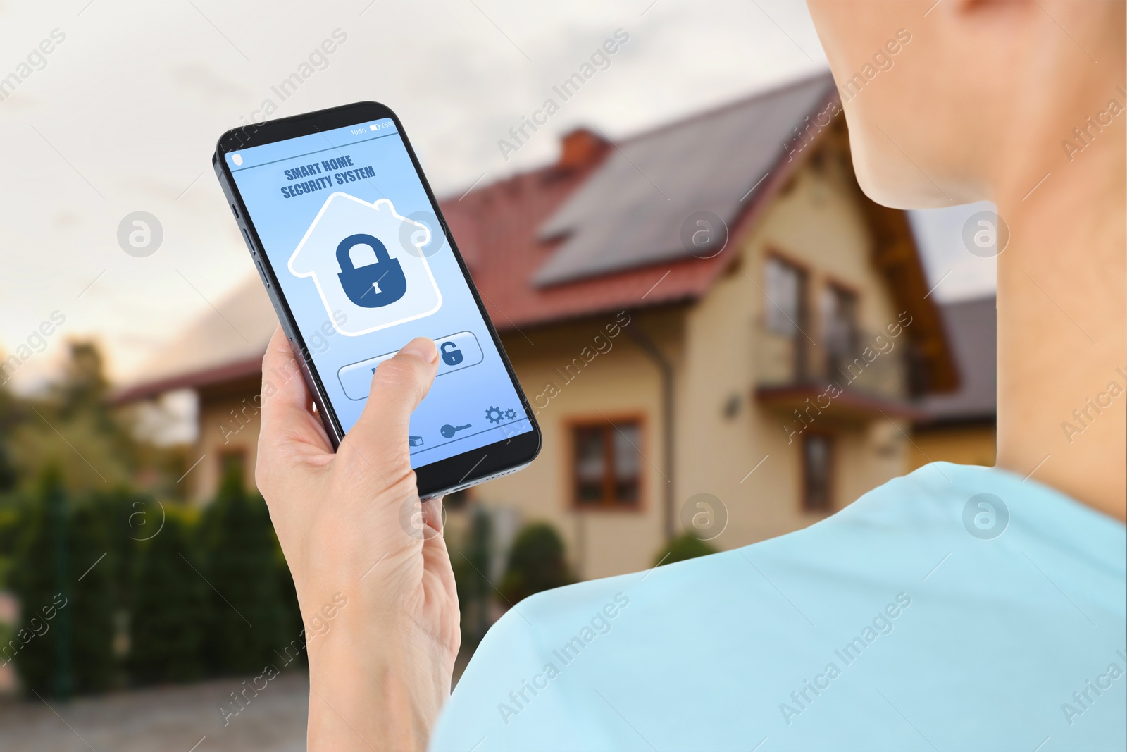 Image of Woman using home security system application on smartphone outdoors, closeup