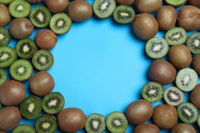 Photo of Frame of cut and whole fresh ripe kiwis on light blue background, flat lay. Space for text