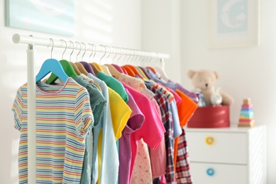 Different child's clothes hanging on rack in room