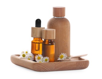 Photo of Bottles of chamomile essential oil and flowers on white background