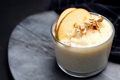 Photo of Delicious rice pudding with apple and almond on grey board, closeup. Space for text