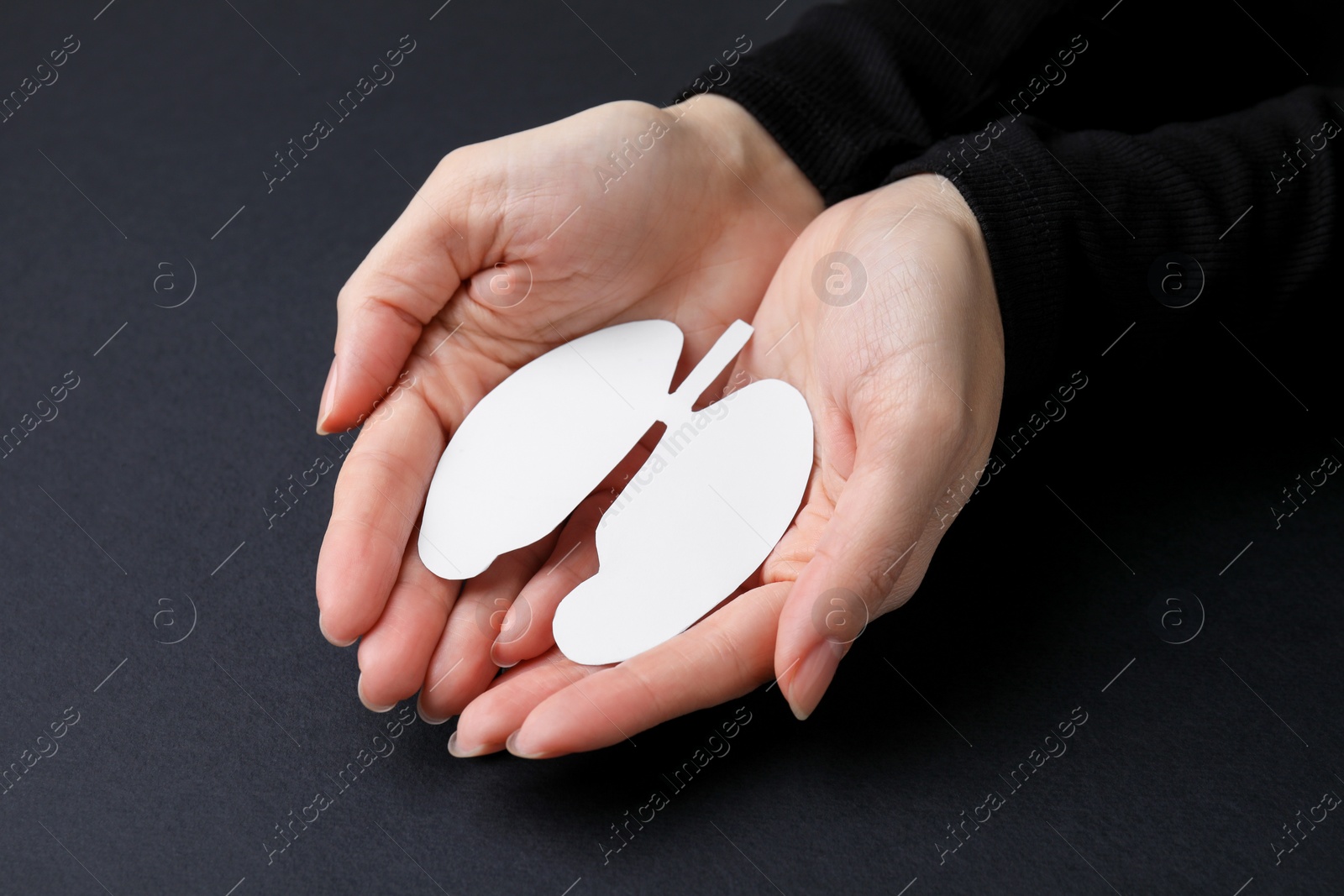 Photo of Quitting smoking concept. Woman holding paper lungs on black background, closeup