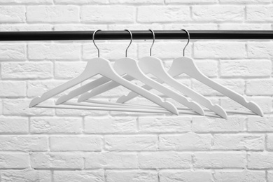 Photo of Clothes hangers on metal rail against brick wall background