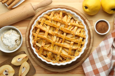 Photo of Tasty homemade quince pie and ingredients on wooden table, flat lay