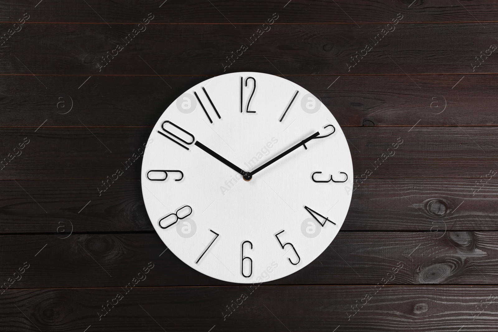 Photo of Stylish analog clock hanging on wooden wall