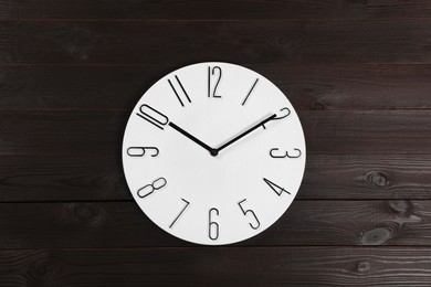 Photo of Stylish analog clock hanging on wooden wall