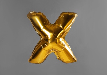 Photo of Golden letter X balloon on grey background