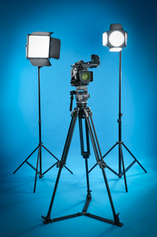Photo of Professional video camera and lighting equipment on blue background