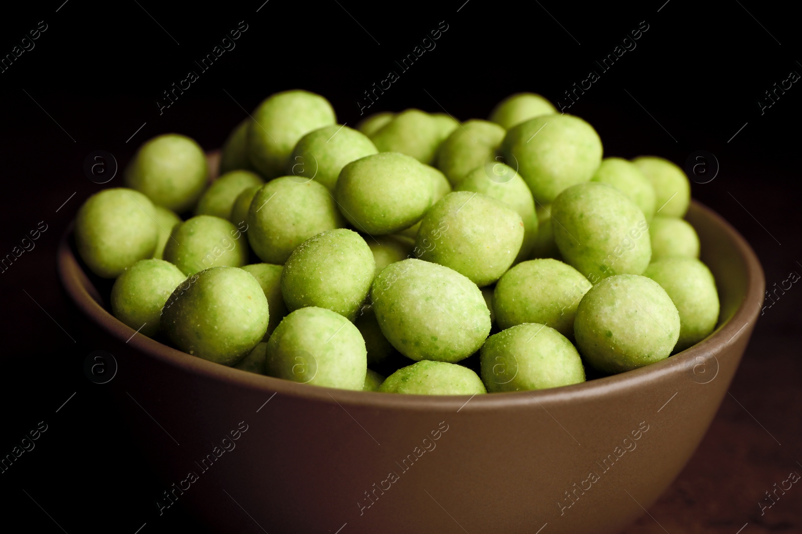 Photo of Tasty wasabi coated peanuts in bowl, closeup