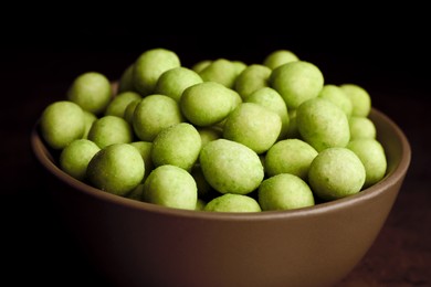 Tasty wasabi coated peanuts in bowl, closeup