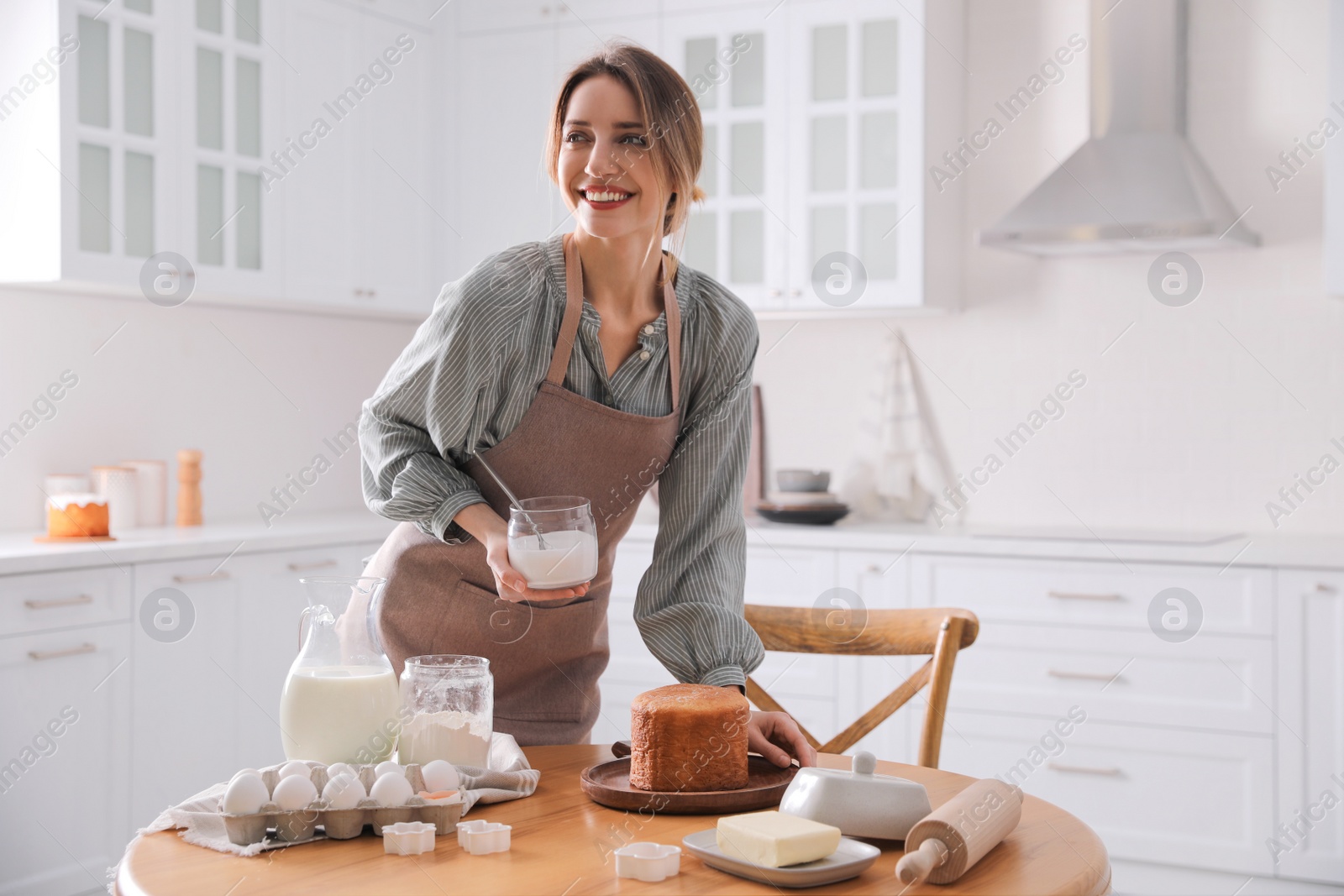 Photo of Young woman making traditional Easter cake in kitchen