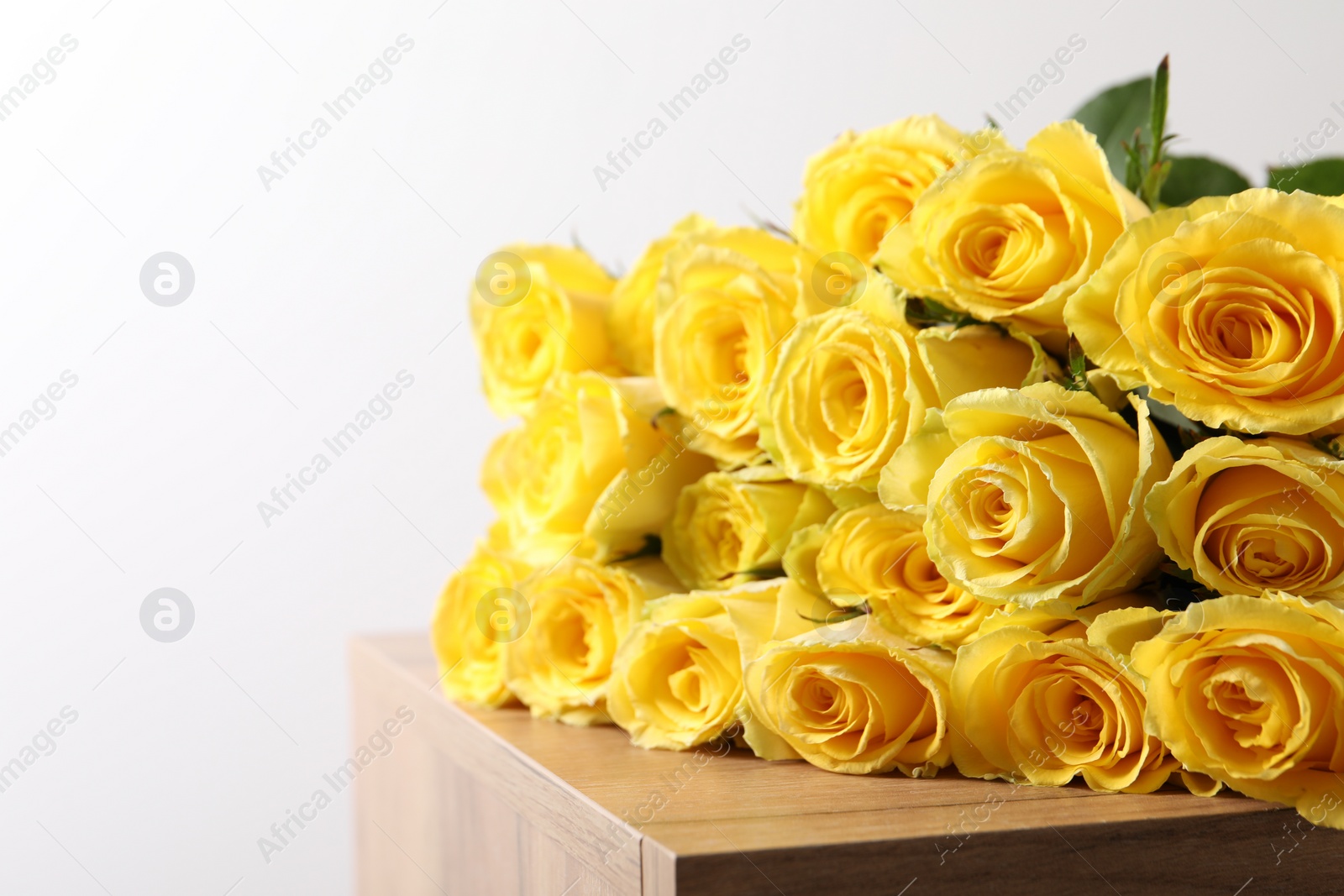 Photo of Beautiful bouquet of yellow roses on wooden table, closeup. Space for text