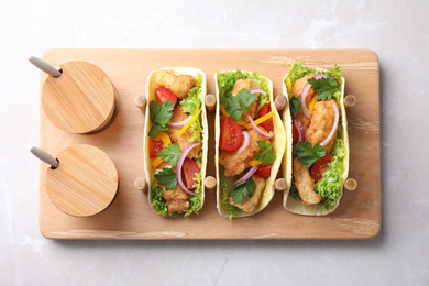 Yummy fish tacos served on marble table, top view