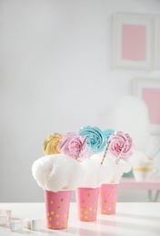 Cups with cotton candy dessert and tasty marshmallow on table, space for text