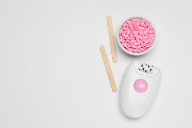 Photo of Modern epilator, sticks and wax on white background, flat lay. Space for text