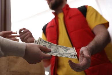 Deliveryman receiving tips from woman indoors, closeup