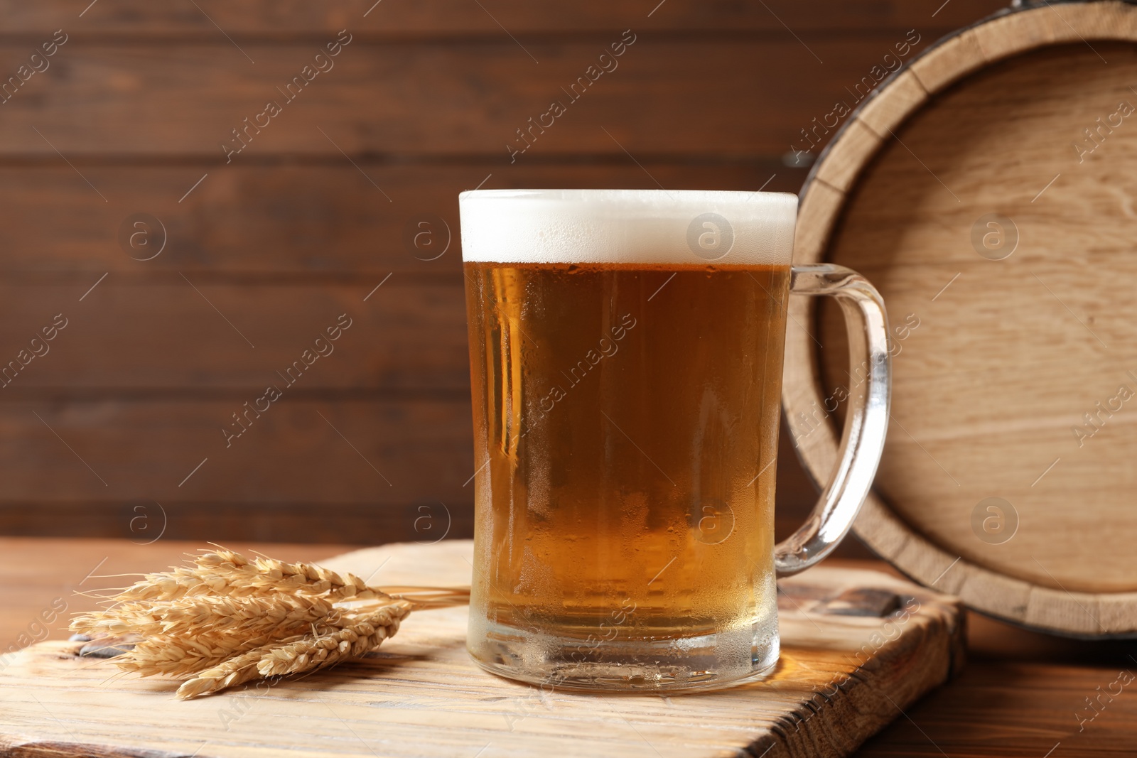 Photo of Glass mug with cold tasty beer and malt on wooden table