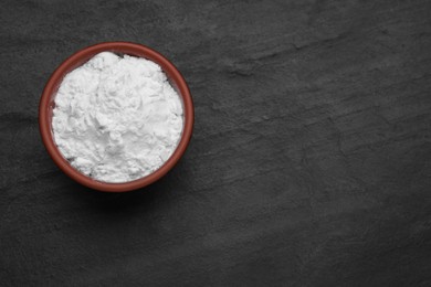 Photo of Bowl of natural starch on black table, top view. Space for text