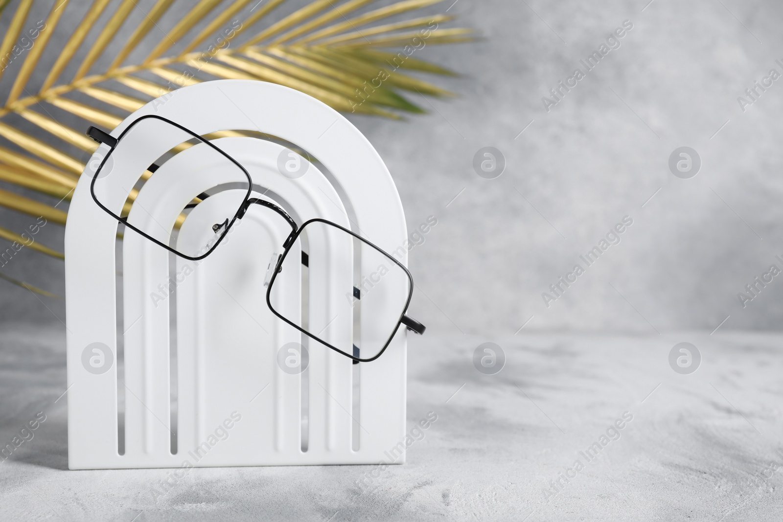 Photo of Stylish presentation of glasses on light grey background, space for text