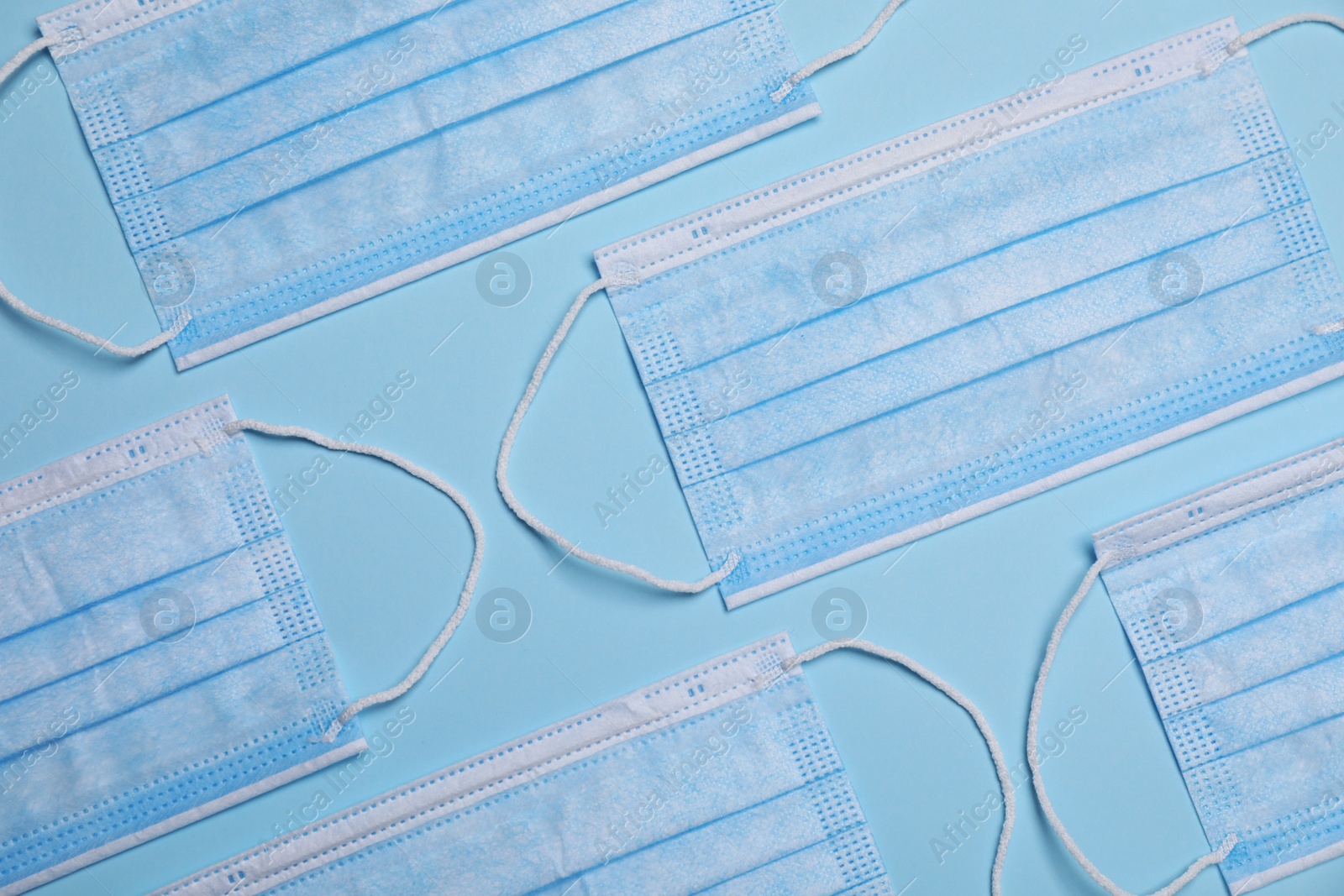 Photo of Protective masks on light blue background, flat lay. Safety equipment