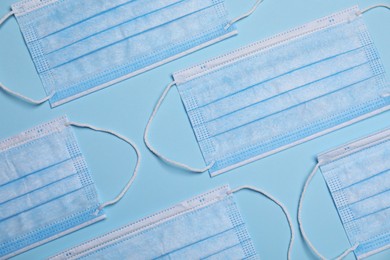 Protective masks on light blue background, flat lay. Safety equipment