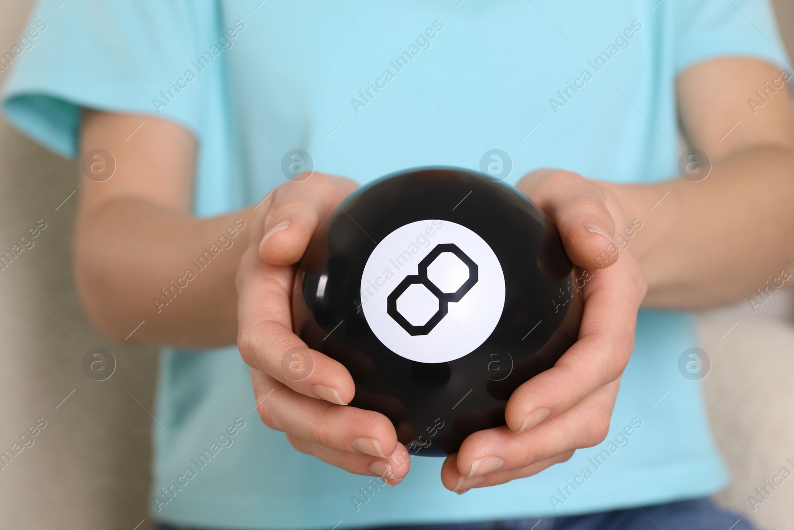 Photo of Woman holding magic eight ball indoors, closeup