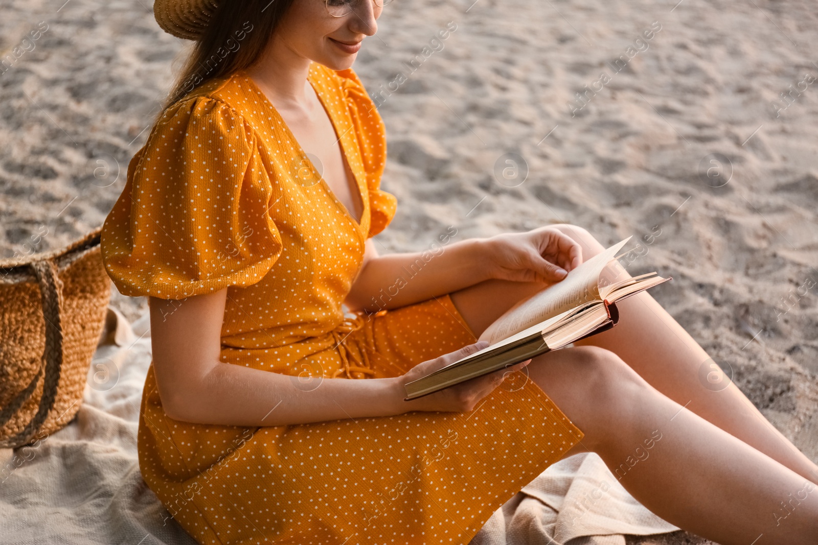 Photo of Young woman reading book on sandy beach