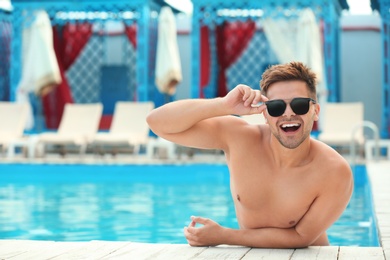 Photo of Handsome young man in swimming pool on sunny day