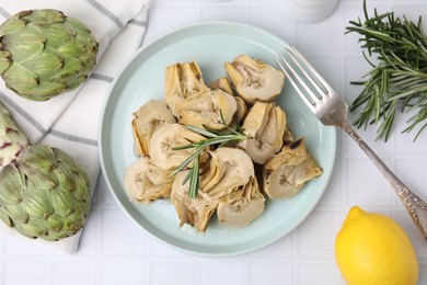 Photo of Pickled and fresh artichokes on white tiled table, flat lay