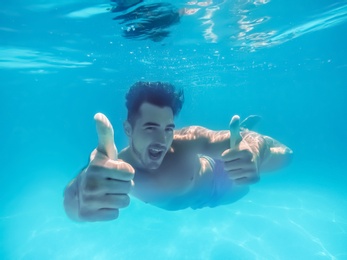 Photo of Handsome young man swimming in pool, underwater view