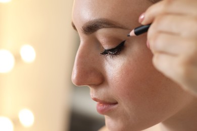 Photo of Makeup product. Woman applying black eyeliner indoors, closeup