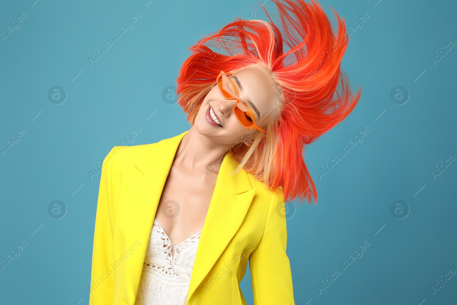 Photo of Beautiful young woman with bright dyed hair shaking head on turquoise background