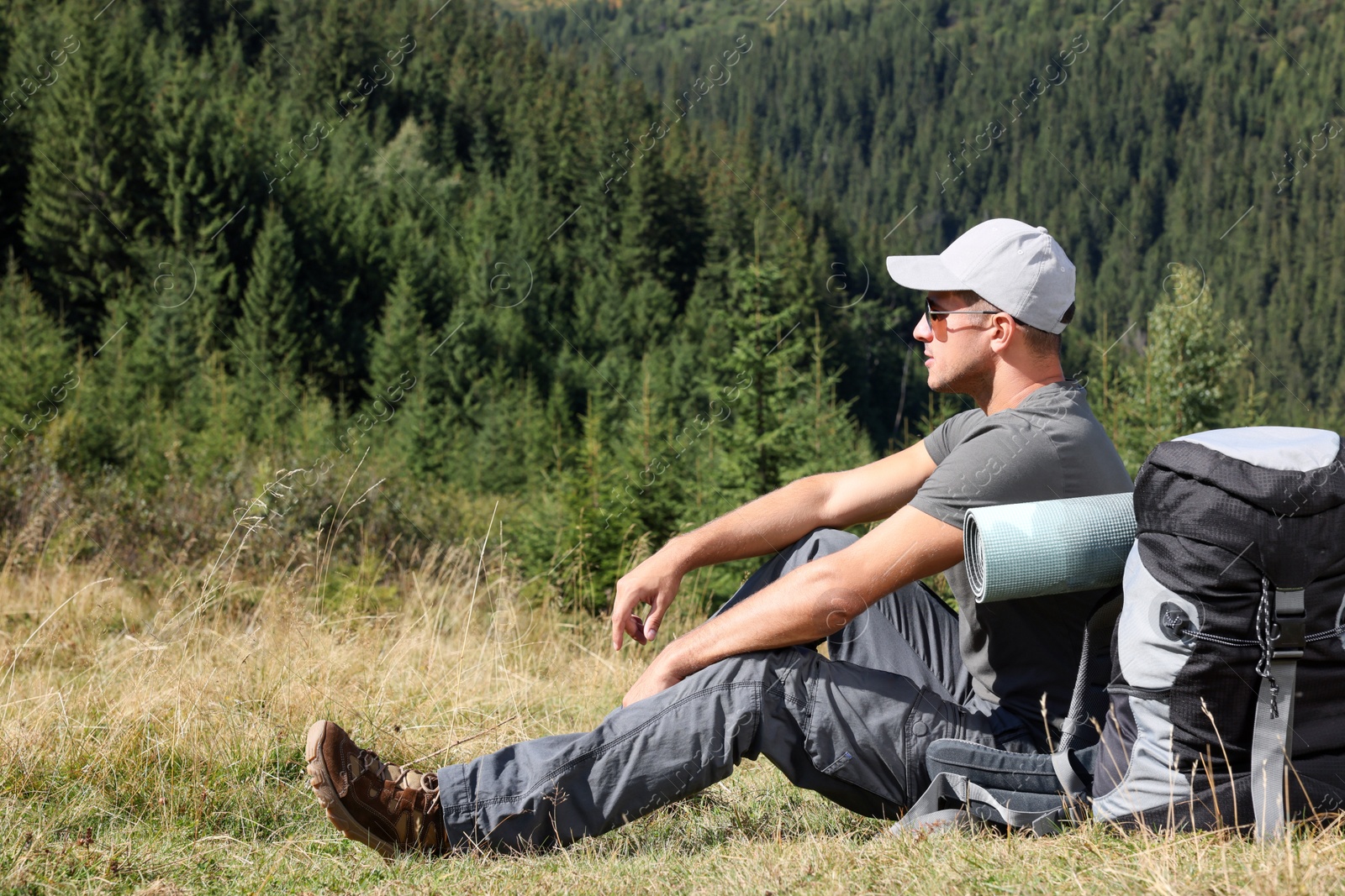 Photo of Tourist with backpack in mountains on sunny day. Space for text