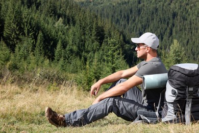 Tourist with backpack in mountains on sunny day. Space for text