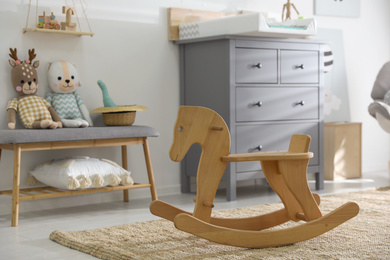 Photo of Beautiful baby room interior with toys, rocking horse and modern changing table