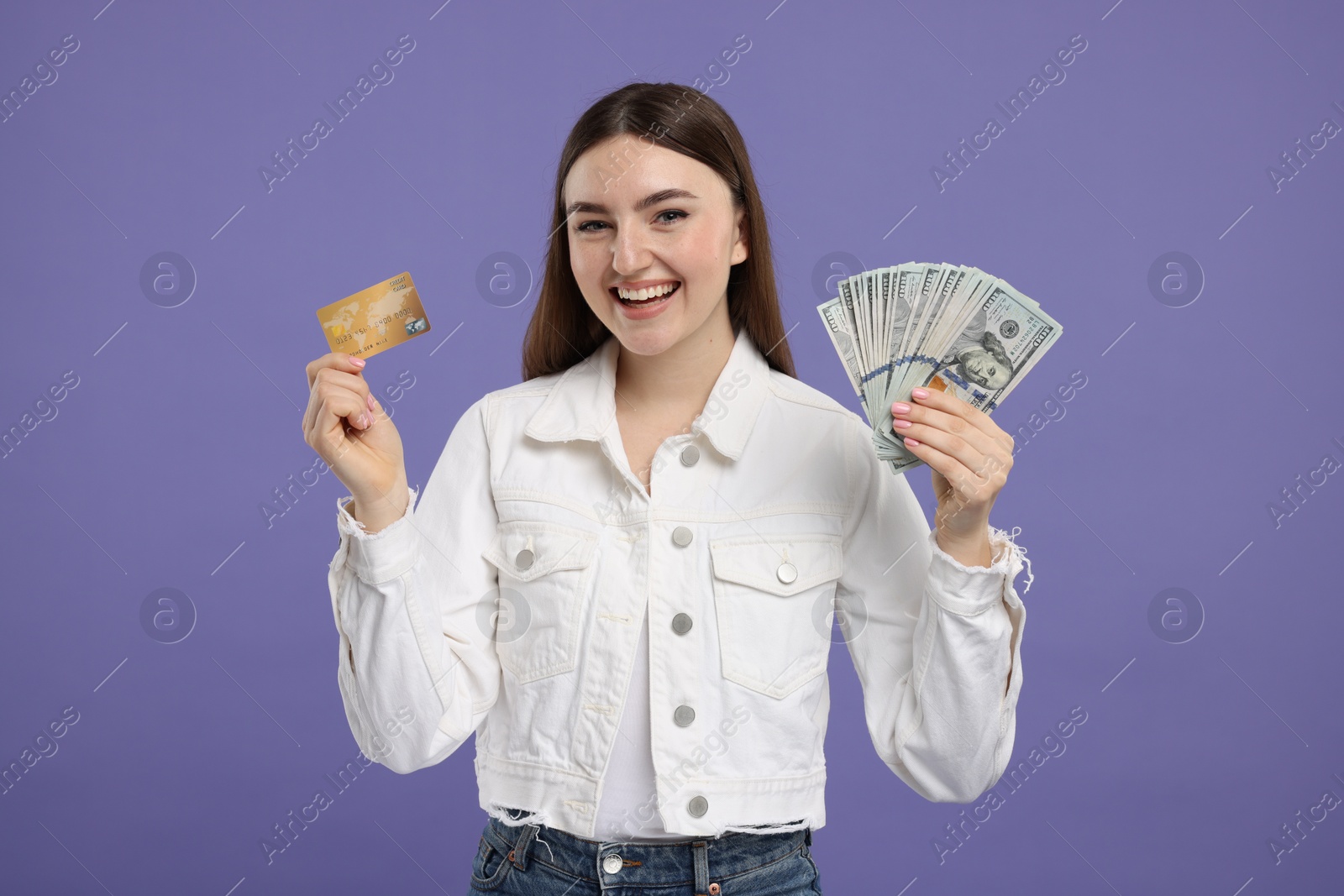 Photo of Happy woman with credit card and dollar banknotes on purple background