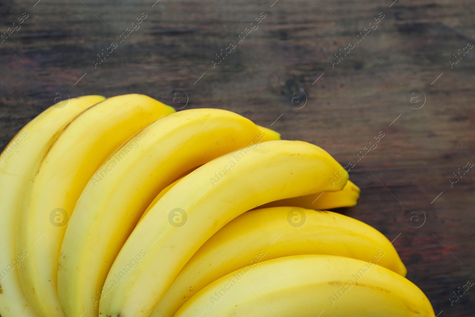 Photo of Bunch of ripe yellow bananas on wooden table, closeup