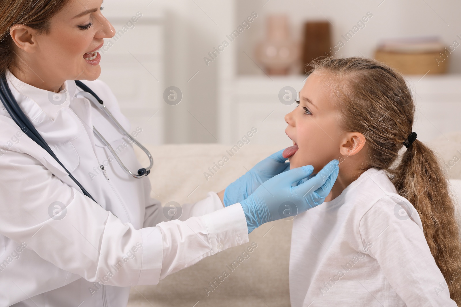 Photo of Smiling doctor examining girl`s oral cavity indoors