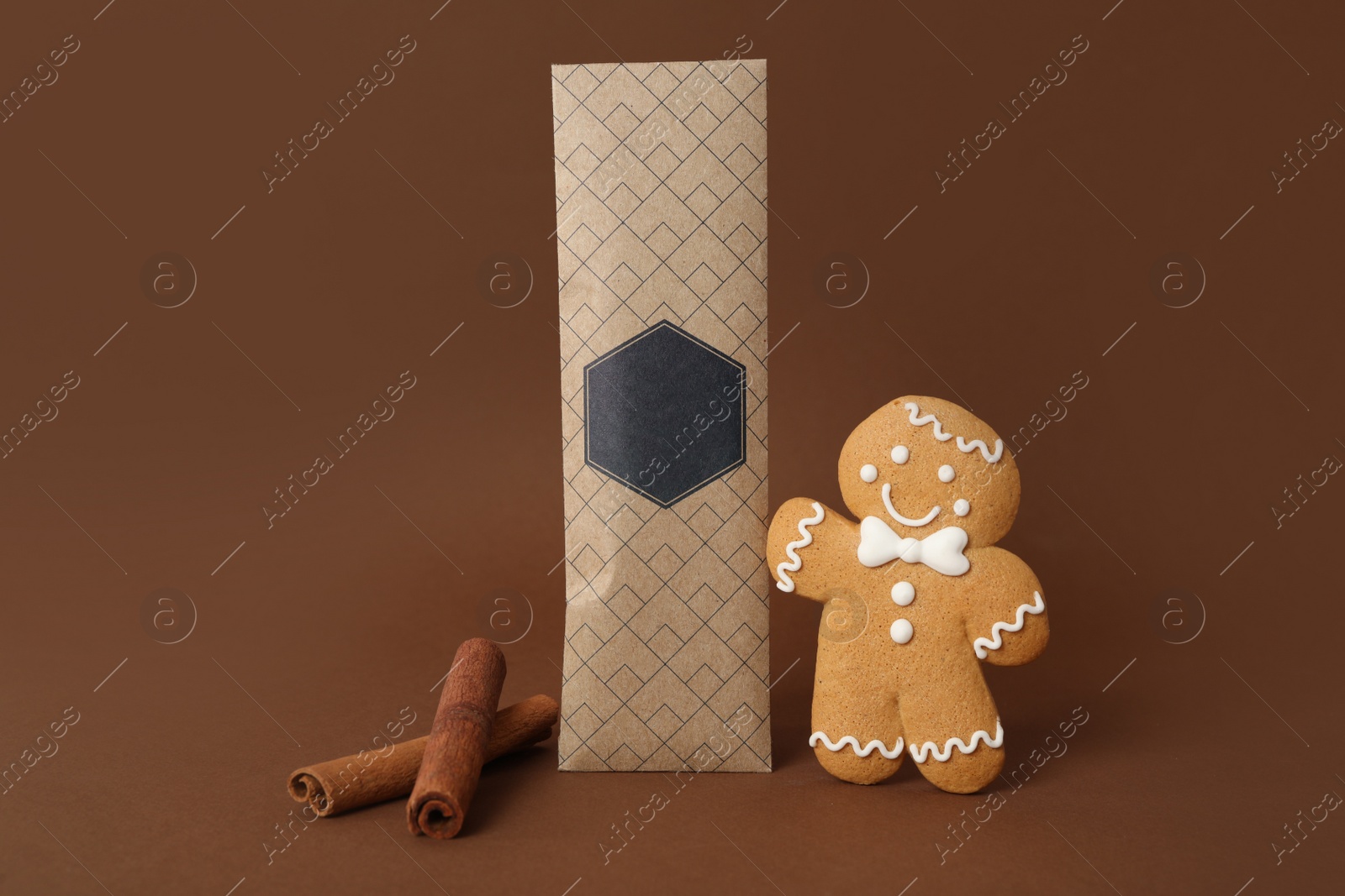 Photo of Scented sachet, cinnamon and gingerbread man on brown background
