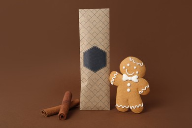 Photo of Scented sachet, cinnamon and gingerbread man on brown background