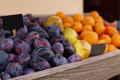 Fresh ripe fruits in wooden crate at market, selective focus