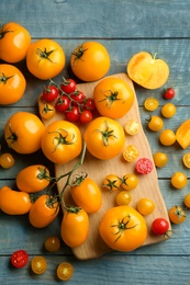 Photo of Ripe yellow and red tomatoes on light blue wooden table, flat lay