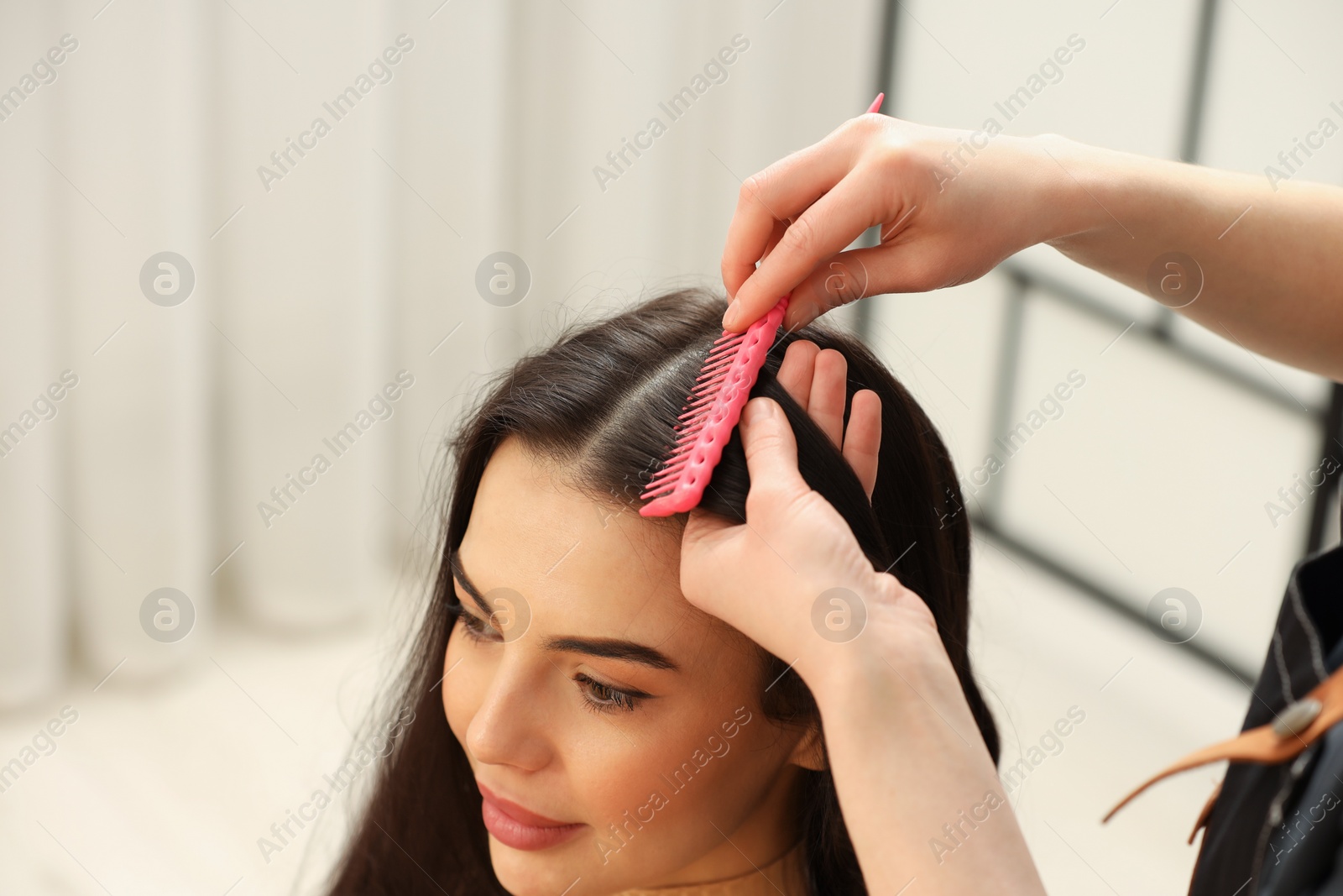 Photo of Professional hairdresser combing woman's hair indoors, closeup. Space for text