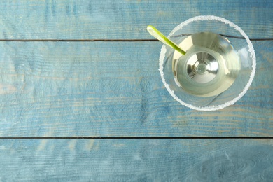 Photo of Glass of Lime Drop Martini cocktail on light blue wooden table, top view. Space for text