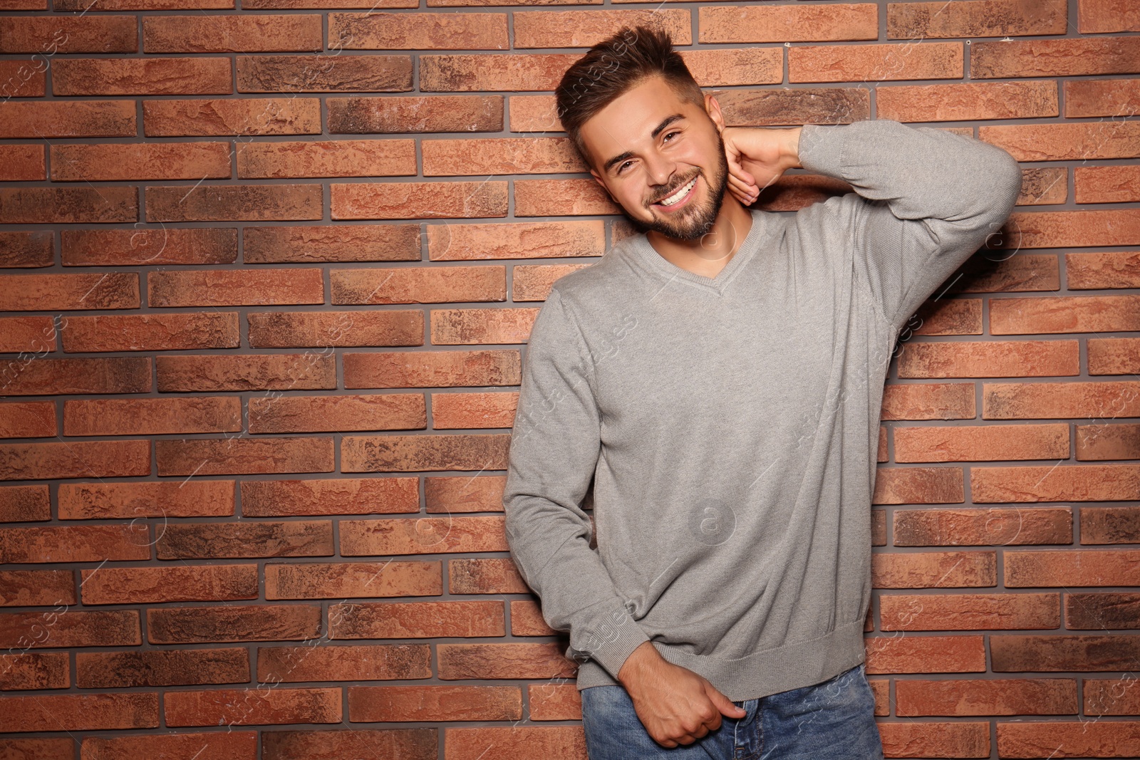 Image of Handsome man wearing warm sweater near brick wall. Space for text