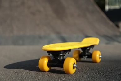 Modern yellow skateboard on asphalt road outdoors, closeup